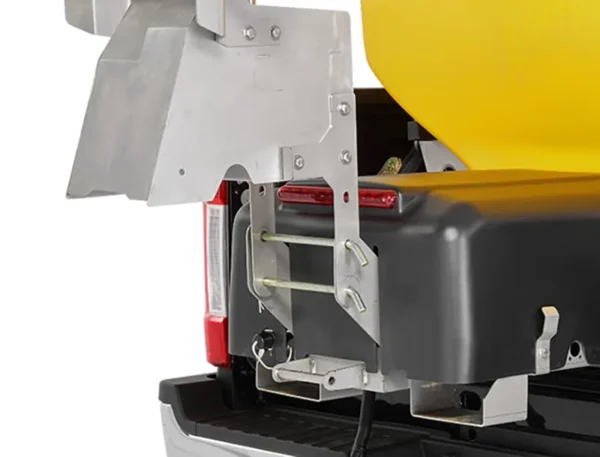 Wessex Snowex Helixx Spreaders | Middlewich Machinery Close-up of a wessex snowex helixx spreader attached to the back of a pickup truck. The yellow spreader is secured with metal brackets and fasteners.